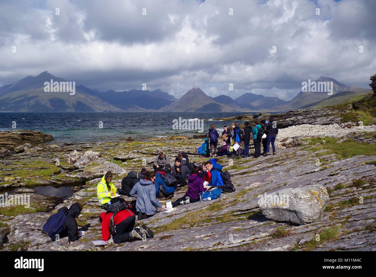 Parte della geologia studenti, sulla Foreshore di Elgol Beach, drammatica Cuillin Hills in background. Isola di Skye, Scotland, Regno Unito. 2017. Foto Stock