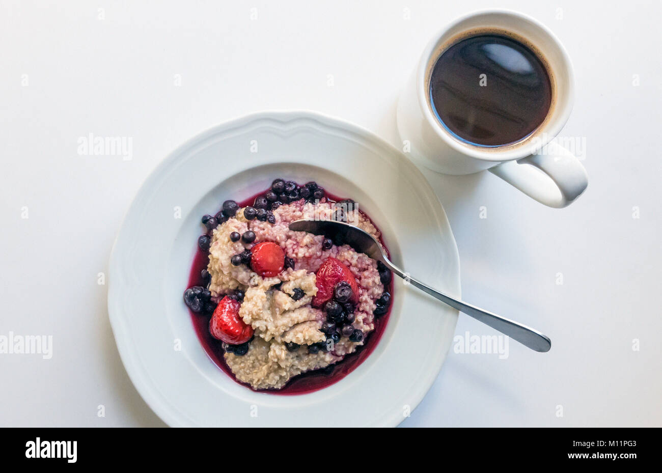 Una tazza di farina d'avena, con frutta e una tazza di caffè nero Foto  stock - Alamy