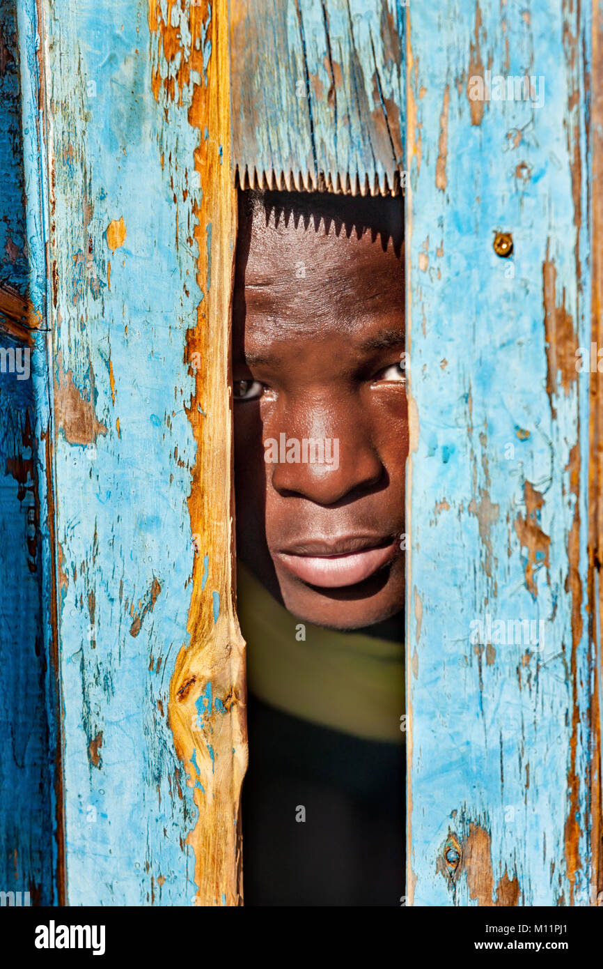 Bambino africano di nascondersi dietro una porta nel villaggio, Botswana Foto Stock