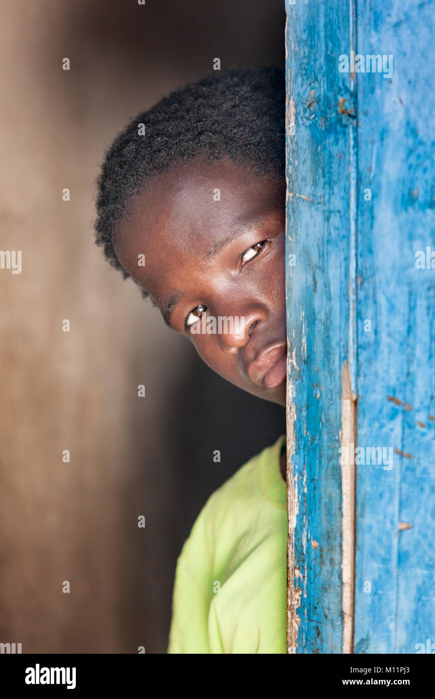 Bambino africano in piedi dietro una porta nel villaggio, Botswana Foto Stock