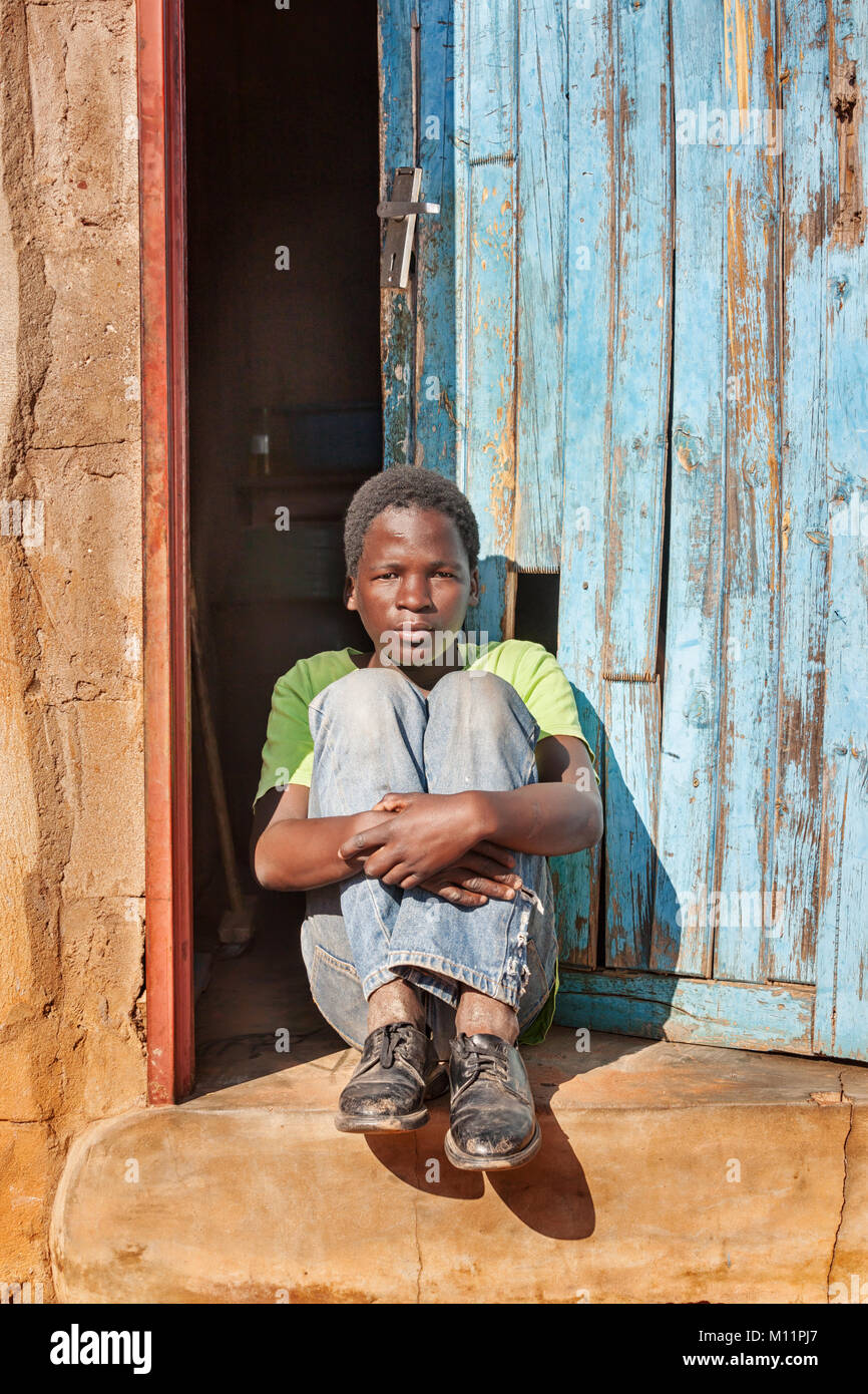 Bambino africano in seduta anteriore se la porta nel villaggio, Botswana Foto Stock