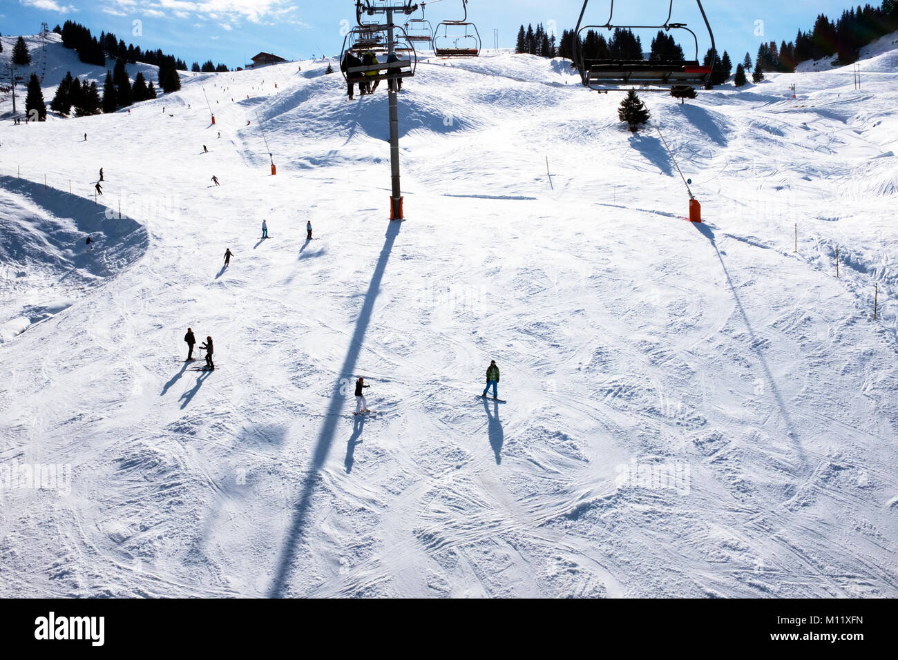 Vista di sciatori dalla seggiovia su un soleggiato tracciato di sci Samoens Francia Foto Stock