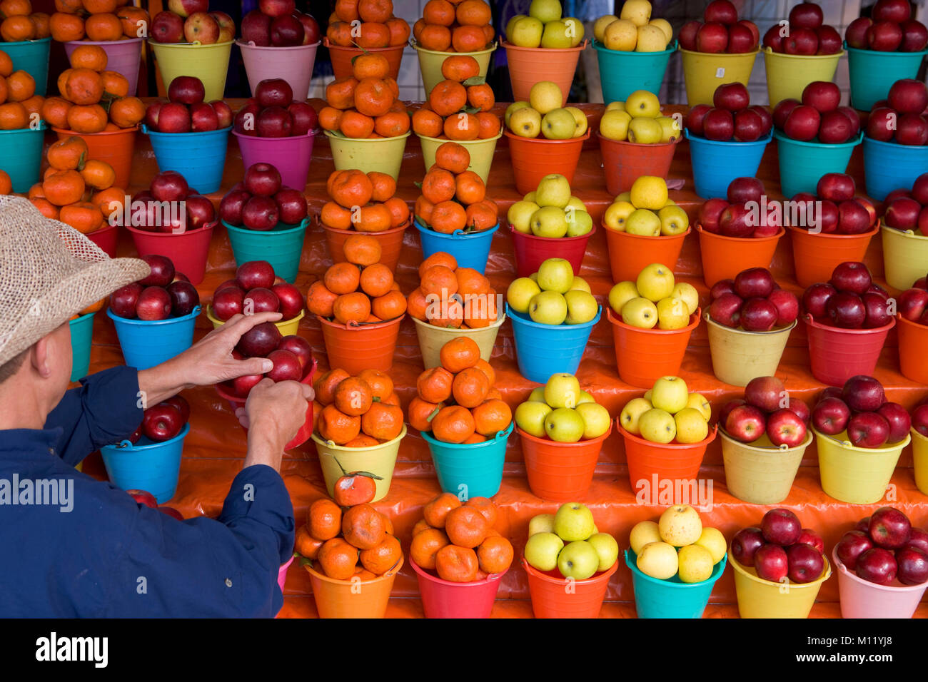Messico. In Chiapas. San Cristobal de las Casas. Multi-colore di bocce di mele sul supporto. Negozio di frutta. L'uomo prendendo la frutta. Foto Stock