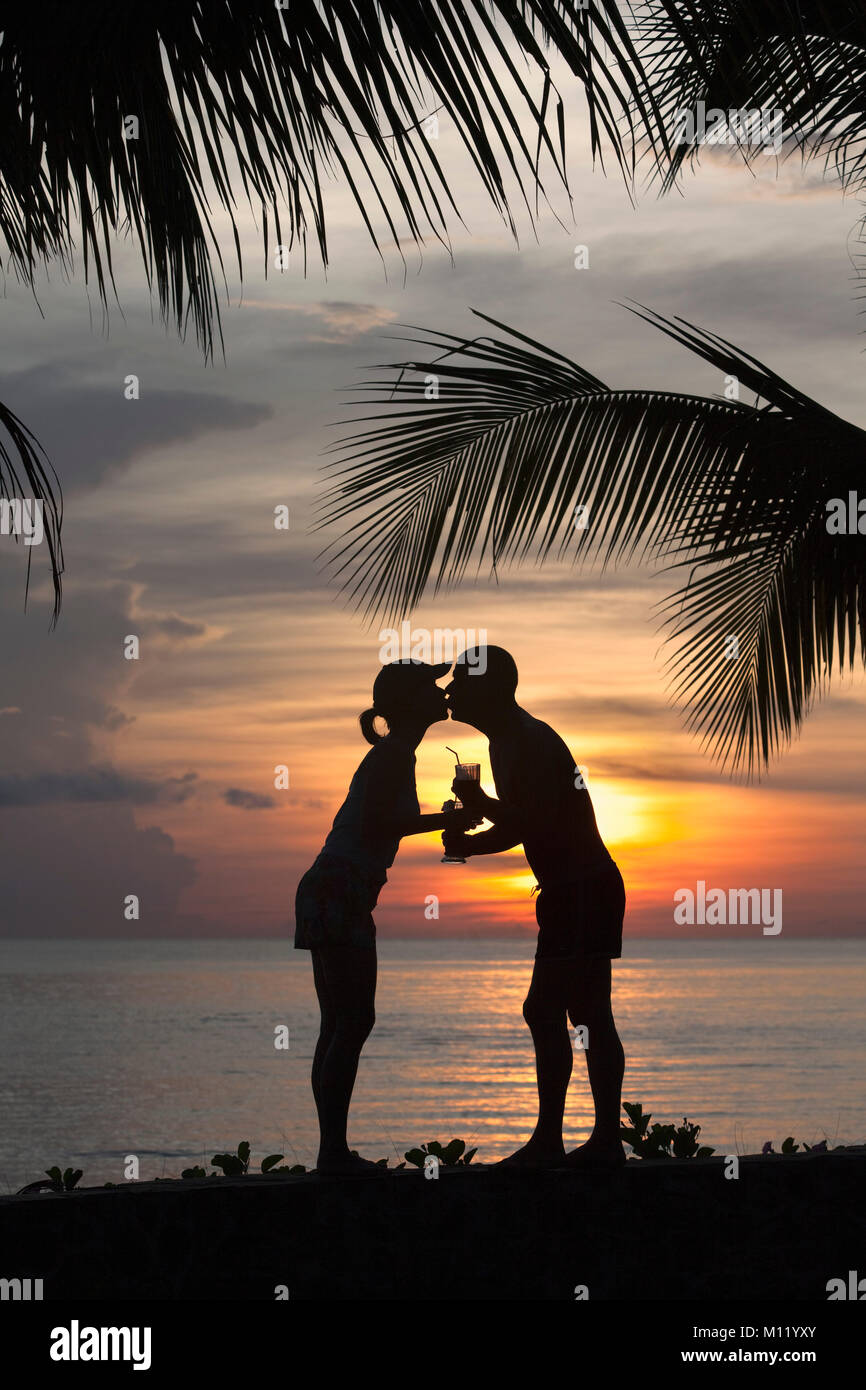 Indonesia, isola di Bali, vicino al villaggio di Tejakula, Gaia Oasis Resort. Giovane con cocktail kissing al tramonto. Foto Stock