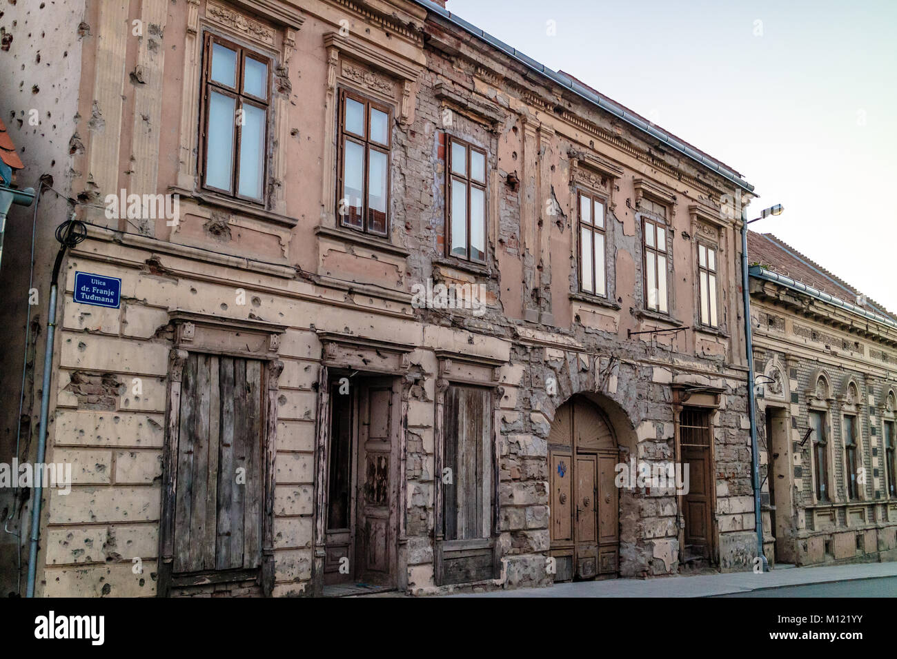 Un edificio a Vukovar riddled con fori di proiettile e un monumento al Croato guerra di indipendenza, Vukovar, Croazia Foto Stock
