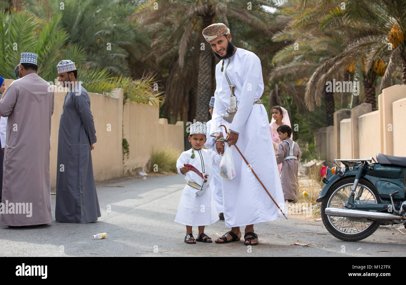 Nizwa, Oman - 26 Giugno 2017: famiglia in abbigliamento tradizionale a un giocattolo sul mercato un giorno di Eid Al Fitr, festa in occasione della fine del mese sacro del Ramadan Foto Stock