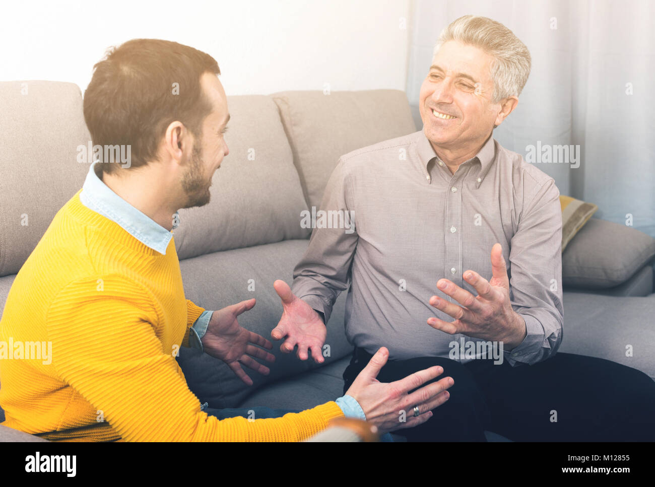 Adulto padre e il suo giovane figlio comunicare calorosamente a casa sul lettino Foto Stock