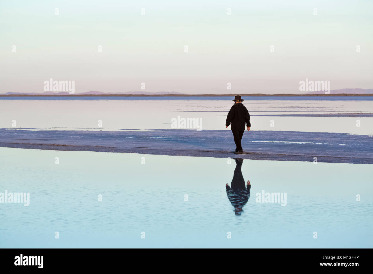 Donna che cammina su uno sputo di terra che si estende fuori in poco profonde di acqua di sale sui laghi salati di Bonneville, in BLM speciale della gestione di ricreazione Area ovest o Foto Stock