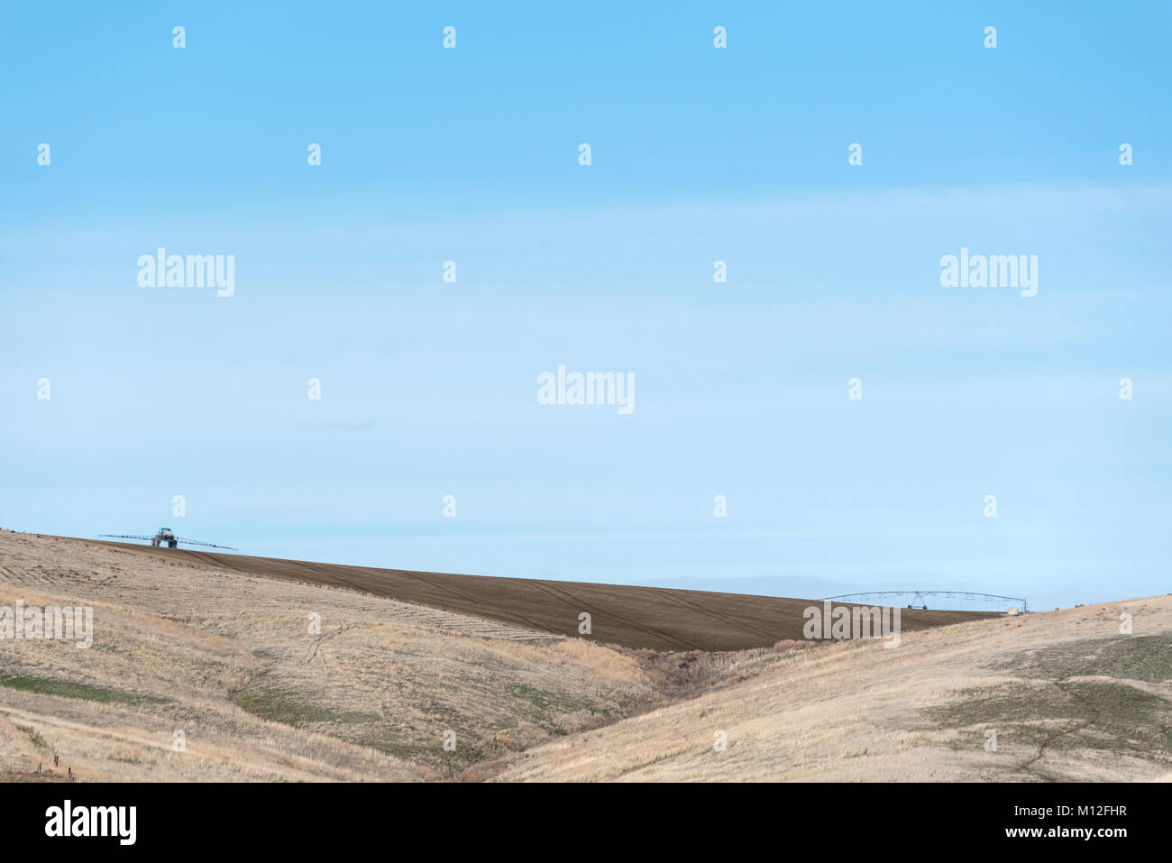 L'agricoltore utilizza un trattore per irroratrice su un campo in Eastern Oregon. Foto Stock