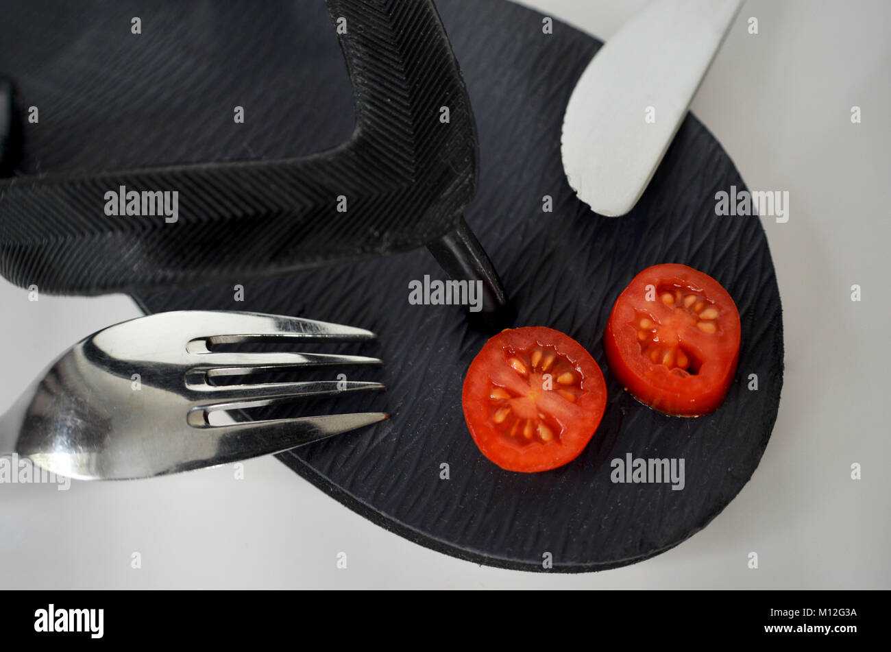 Il flip flop con pomodoro e il coltello e forchetta Foto Stock