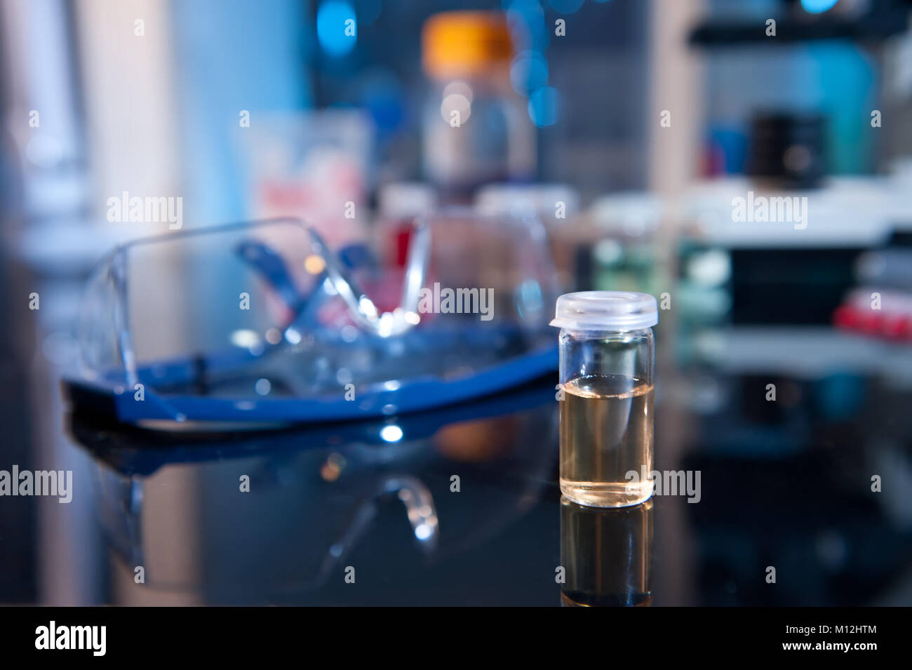 Fiala con del liquido giallo ed una coppia ot pretective bicchieri in laboatory scientifica Foto Stock