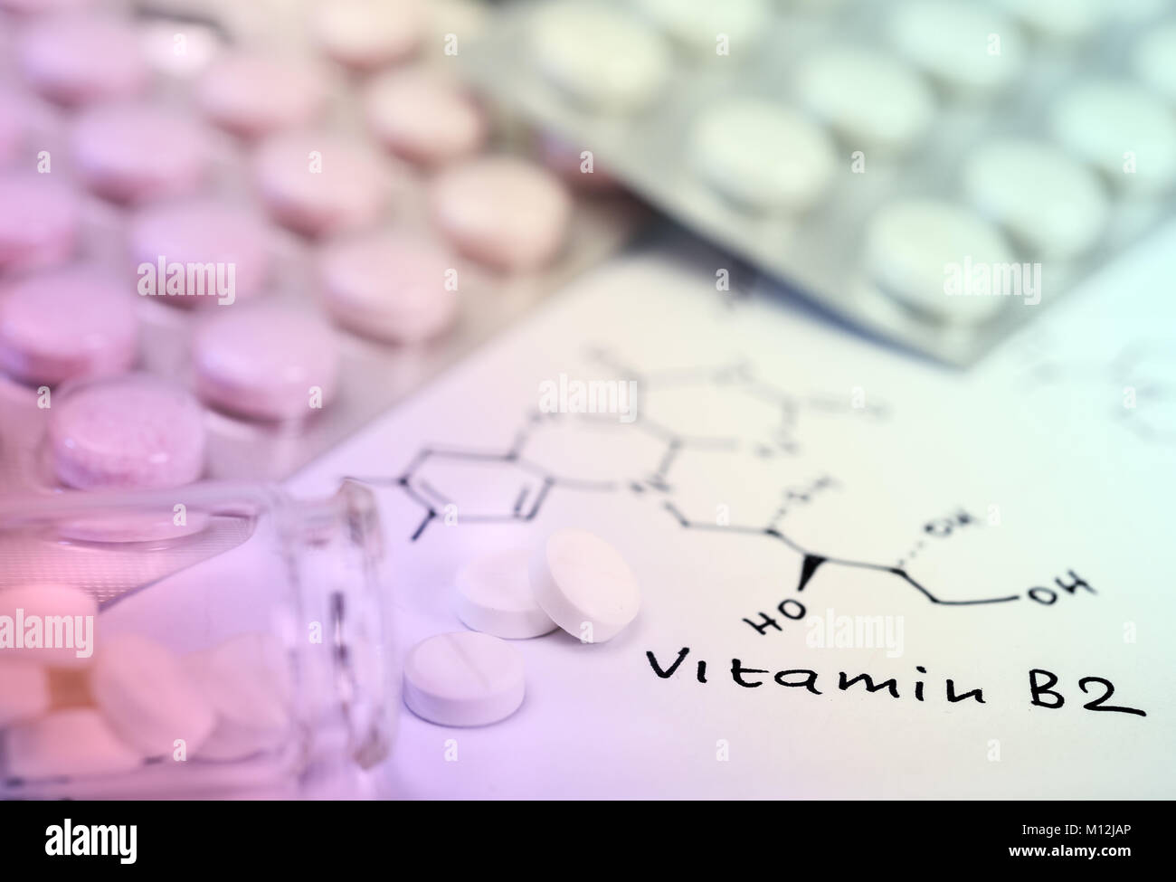 Varie pastiglie sulla carta con formula chimica della vitamina B2 Foto Stock