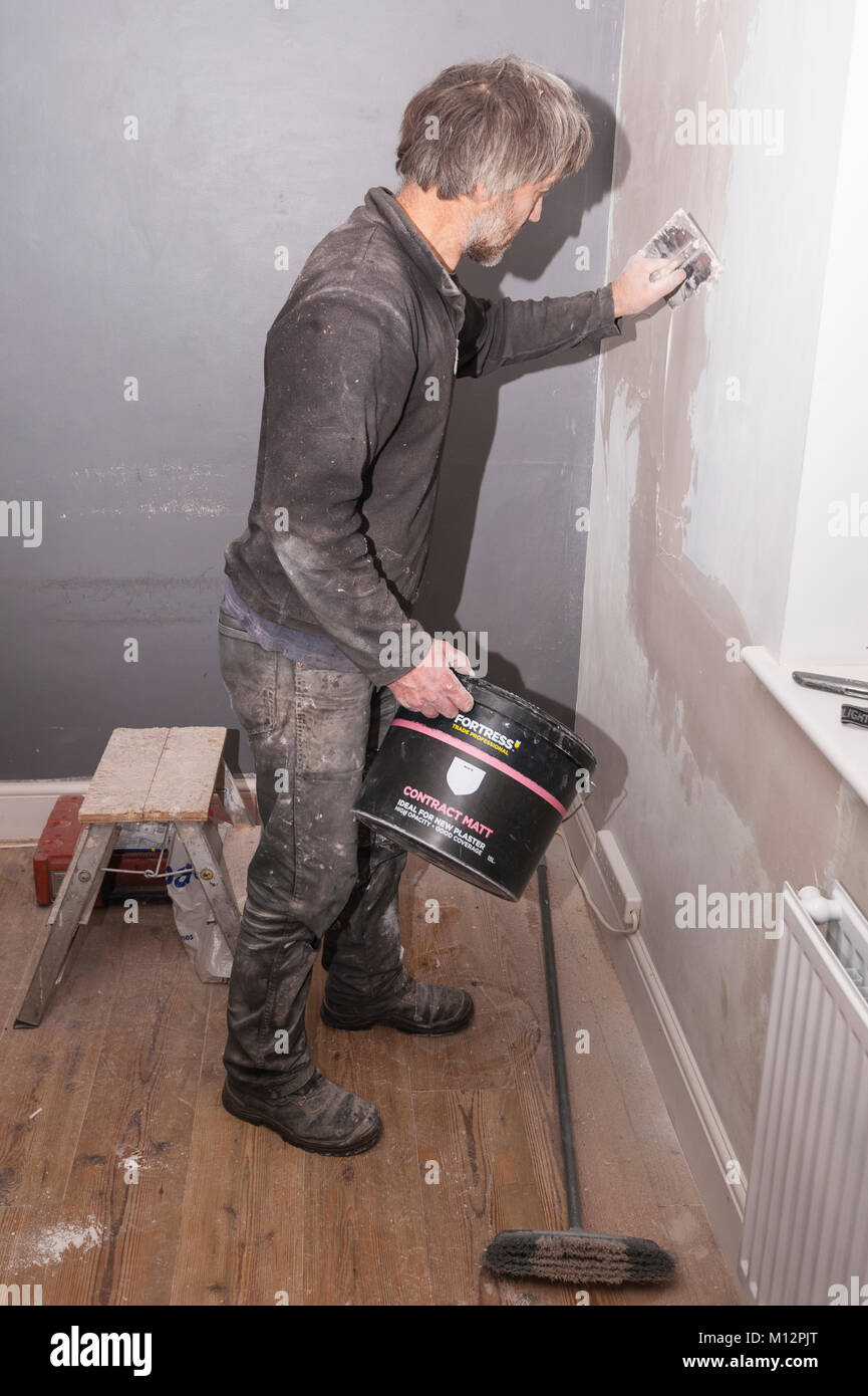 Un uomo intonacatura alcune crepe in un muro nel Regno Unito Foto Stock