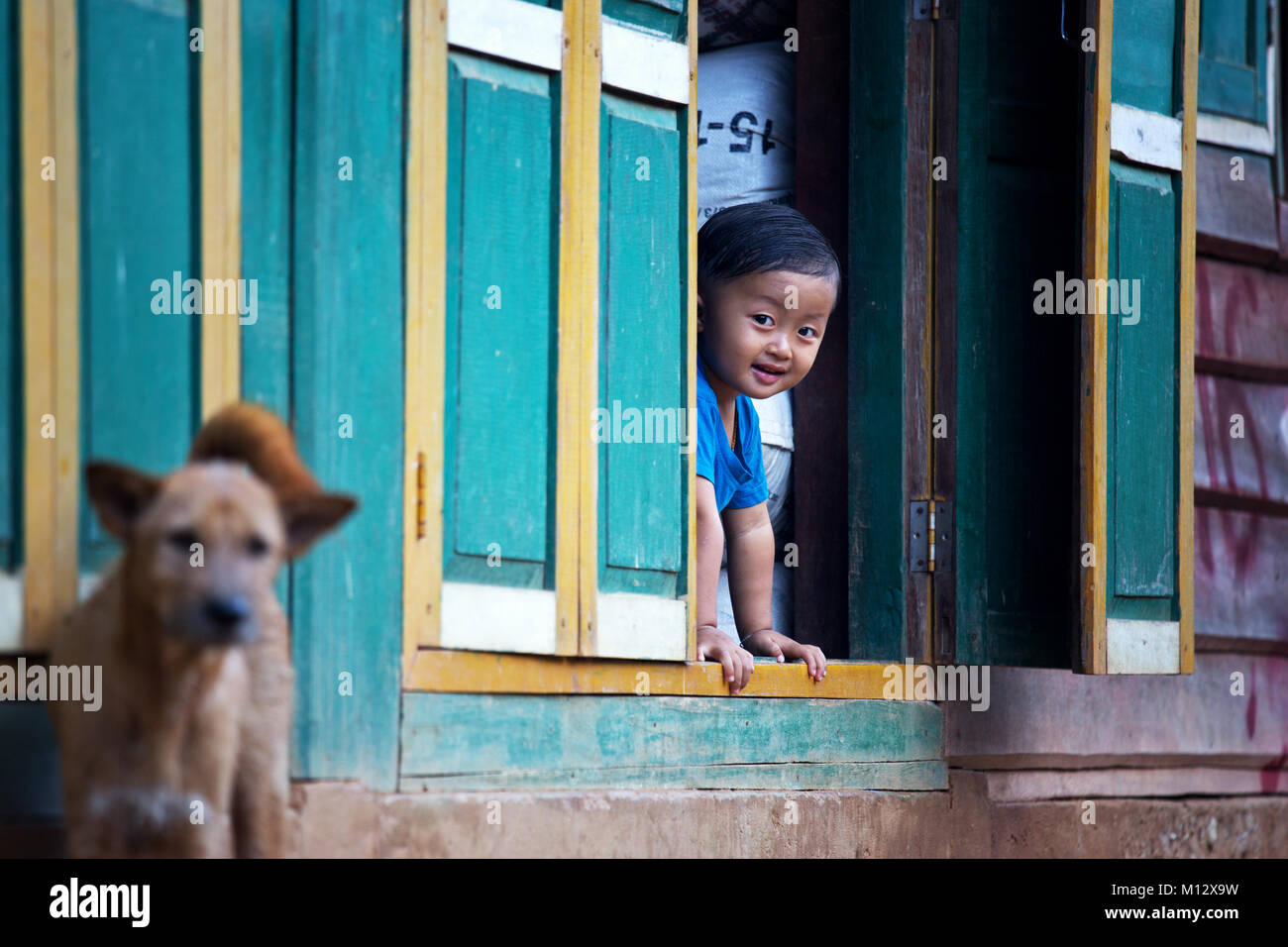 Giovane ragazzo in un remoto villaggio nel nord del Laos è di guardare attraverso una finestra, Indocina, Asia Foto Stock
