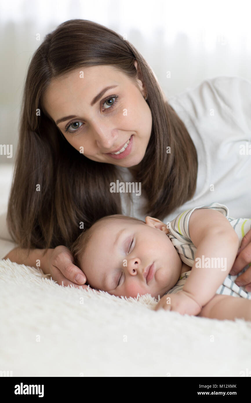 Ritratto di Madre bella con i suoi 7 mesi di età bambino dorme nel letto Foto Stock