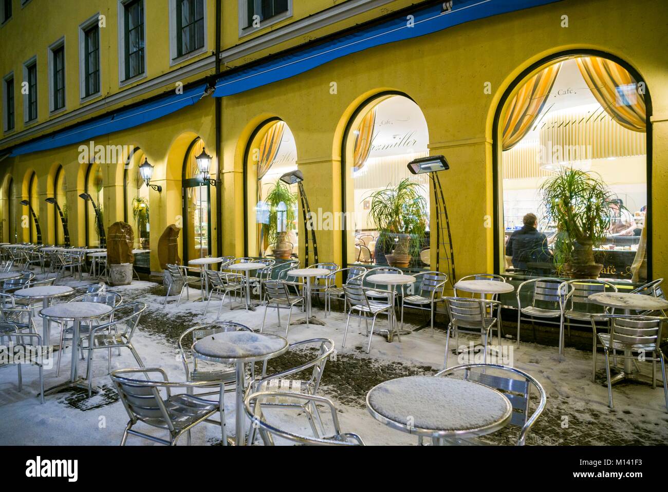 In Germania, in Baviera, Monaco di Baviera, Funf Hofe lussuoso shopping centre, outdoor cafe sotto la neve, sera Foto Stock