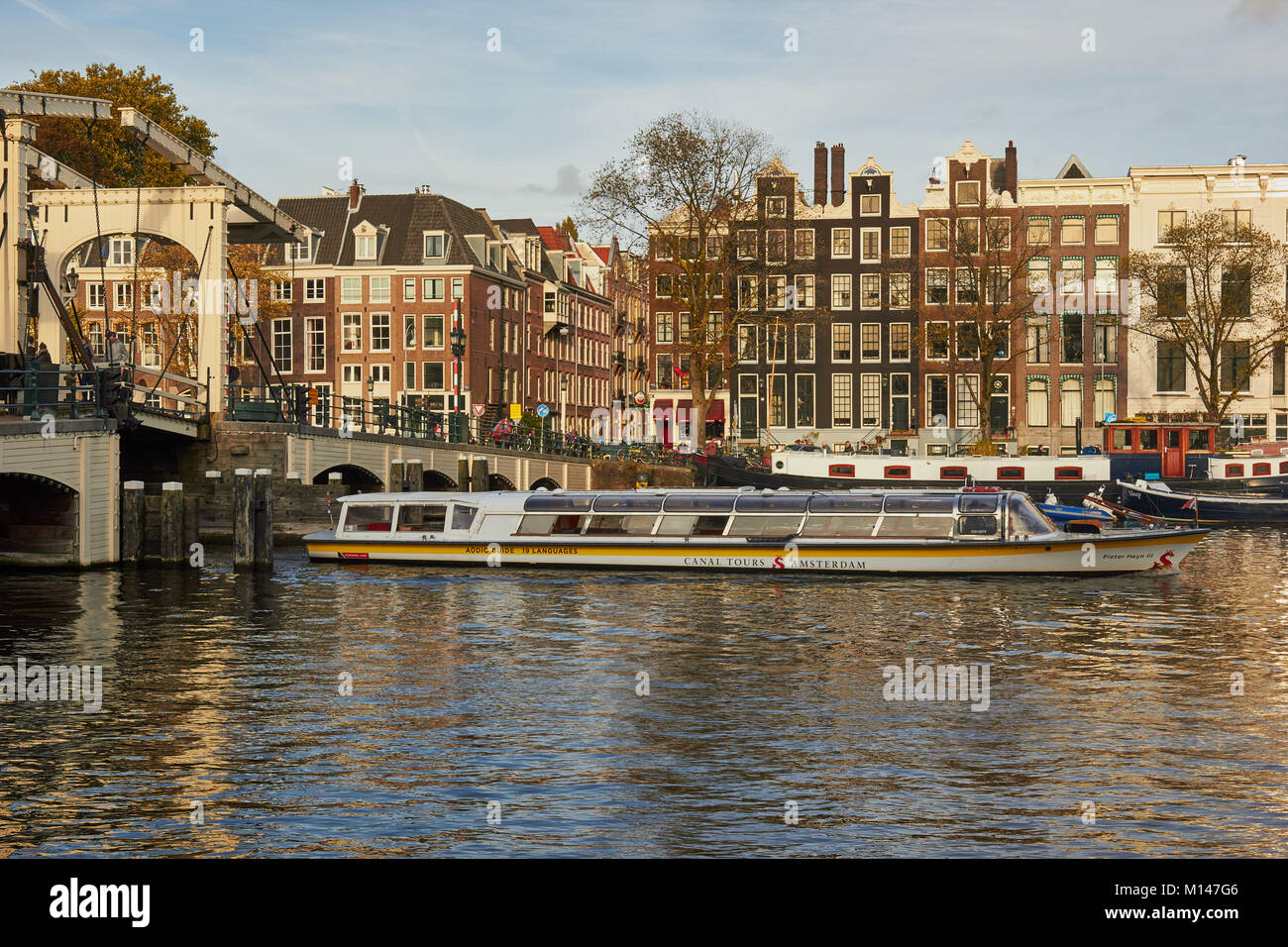 Canal Tour di viaggio in barca attraverso il Magere Brug (skinny bridge) una bicicletta pedonale ponte mobile sul fiume Amstel di Amsterdam, Paesi Bassi Foto Stock