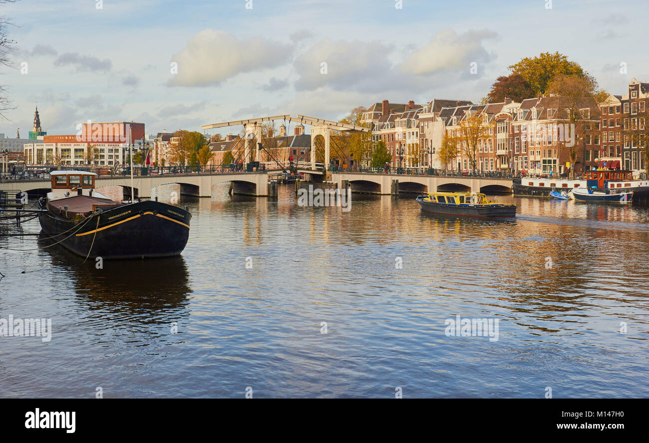Vista lungo il fiume Amstel verso Magere Brug (skinny bridge) una bicicletta pedonale ponte mobile sul fiume Amstel di Amsterdam, Paesi Bassi Foto Stock