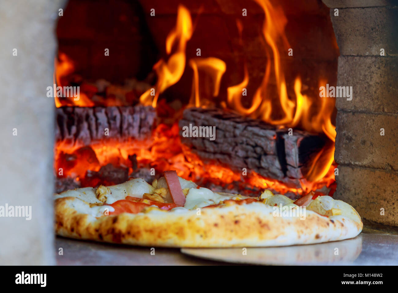 Gourmet Pizza esce dalla pizza al forno a legna forno in ristorante Foto Stock