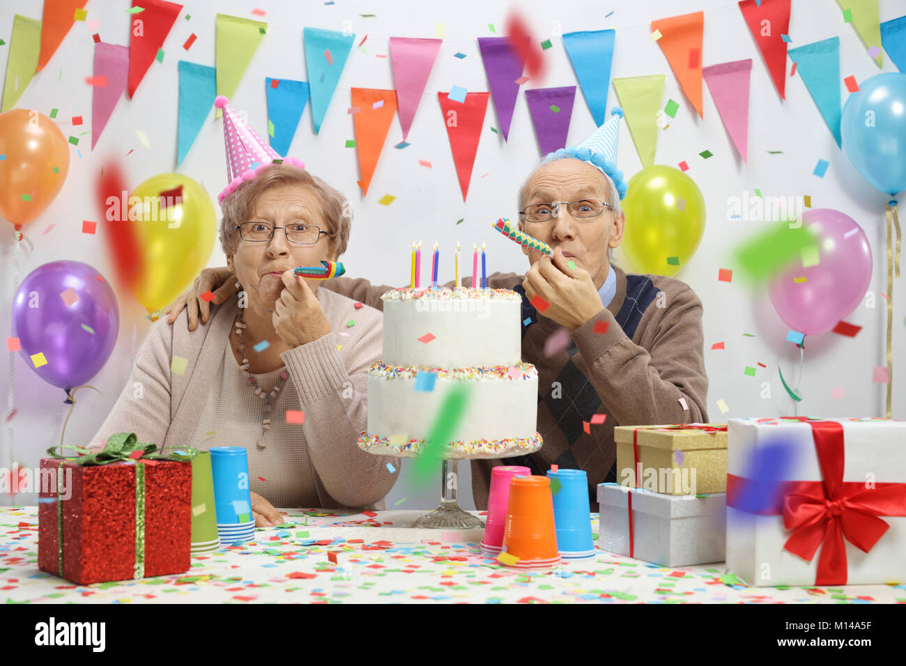 Coppia di anziani per festeggiare un compleanno con parte di corna e una fetta di torta Foto Stock