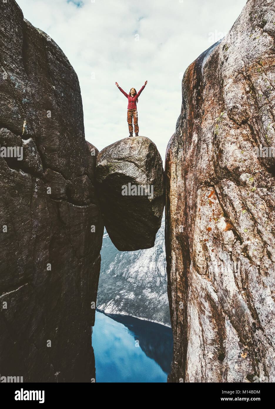 Turista su Kjeragbolten mani alzate viaggi in Norvegia Kjerag montagne extreme vacanze turismo avventura felice emozioni concetto di successo Foto Stock