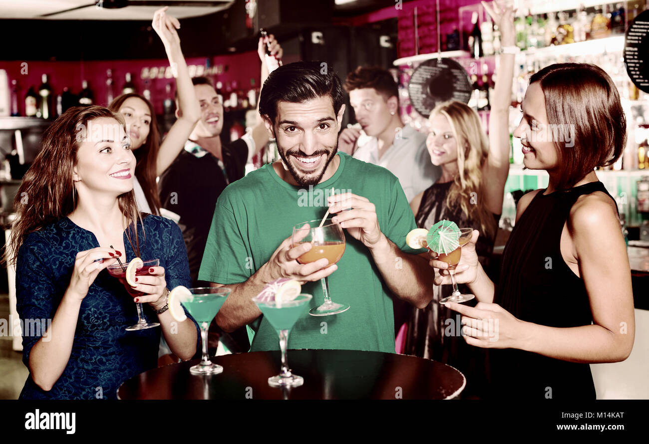 Maschio adulto con due donne stanno parlando e bevendo un cocktail sulla parte. Foto Stock