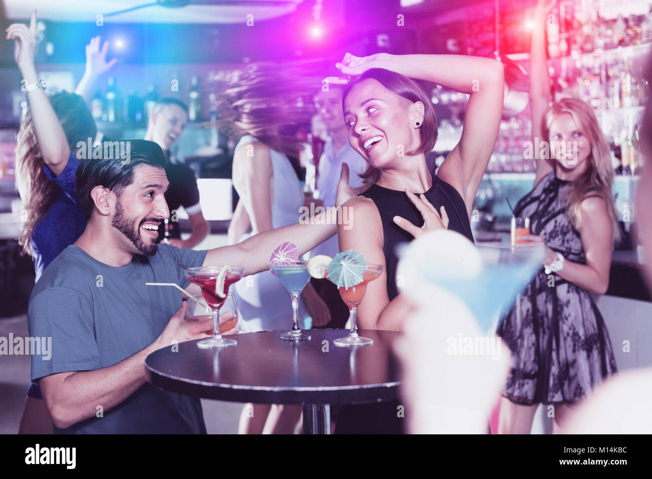 Uomo positivo con giovani donne stanno godendo il partito in bar. Foto Stock