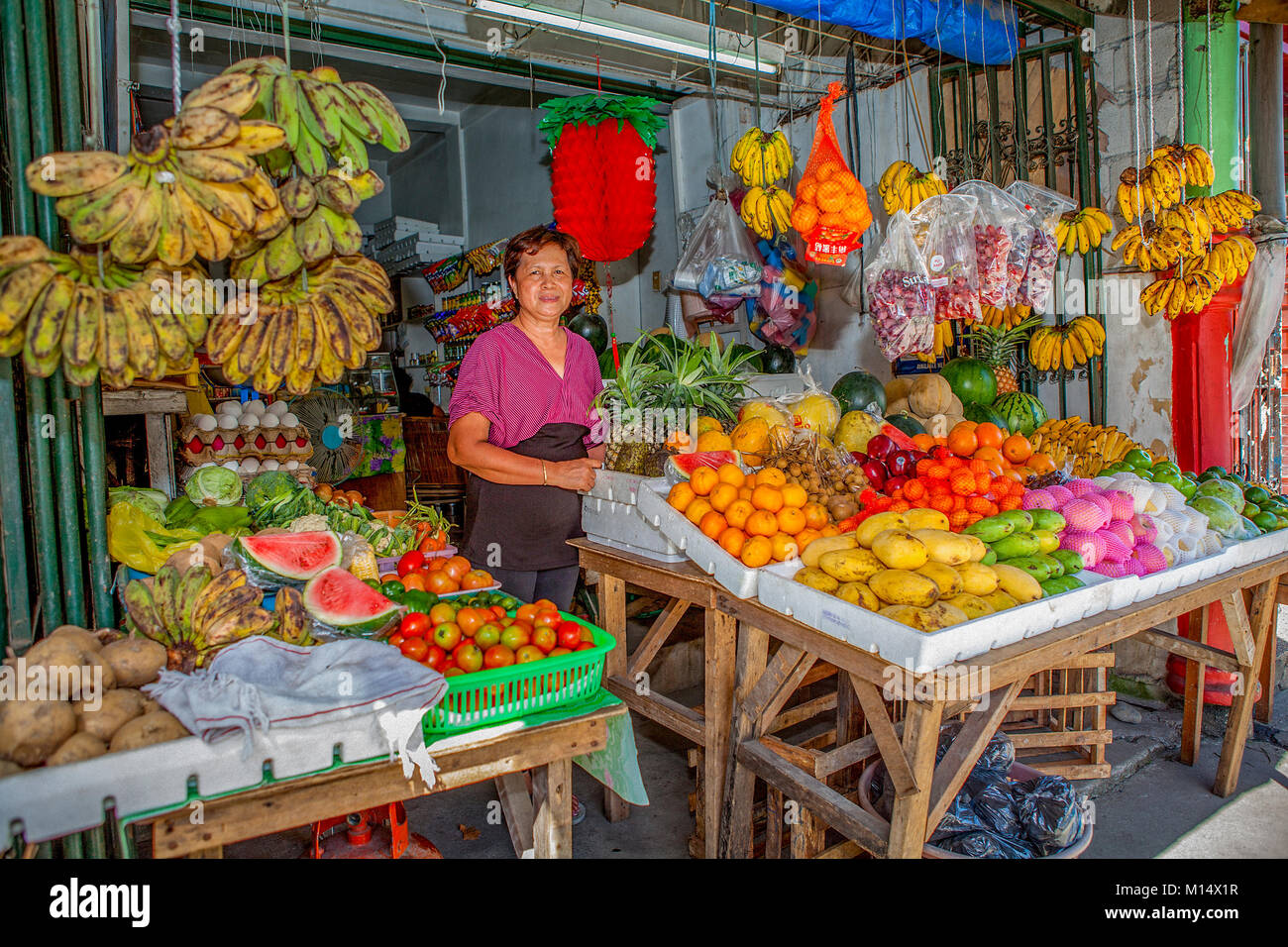 Una varietà di localmente coltivati a frutta e verdura sono venduti da una donna filippina a lei in stallo il mercato pubblico in Barretto, Luzon, Filippine. Foto Stock