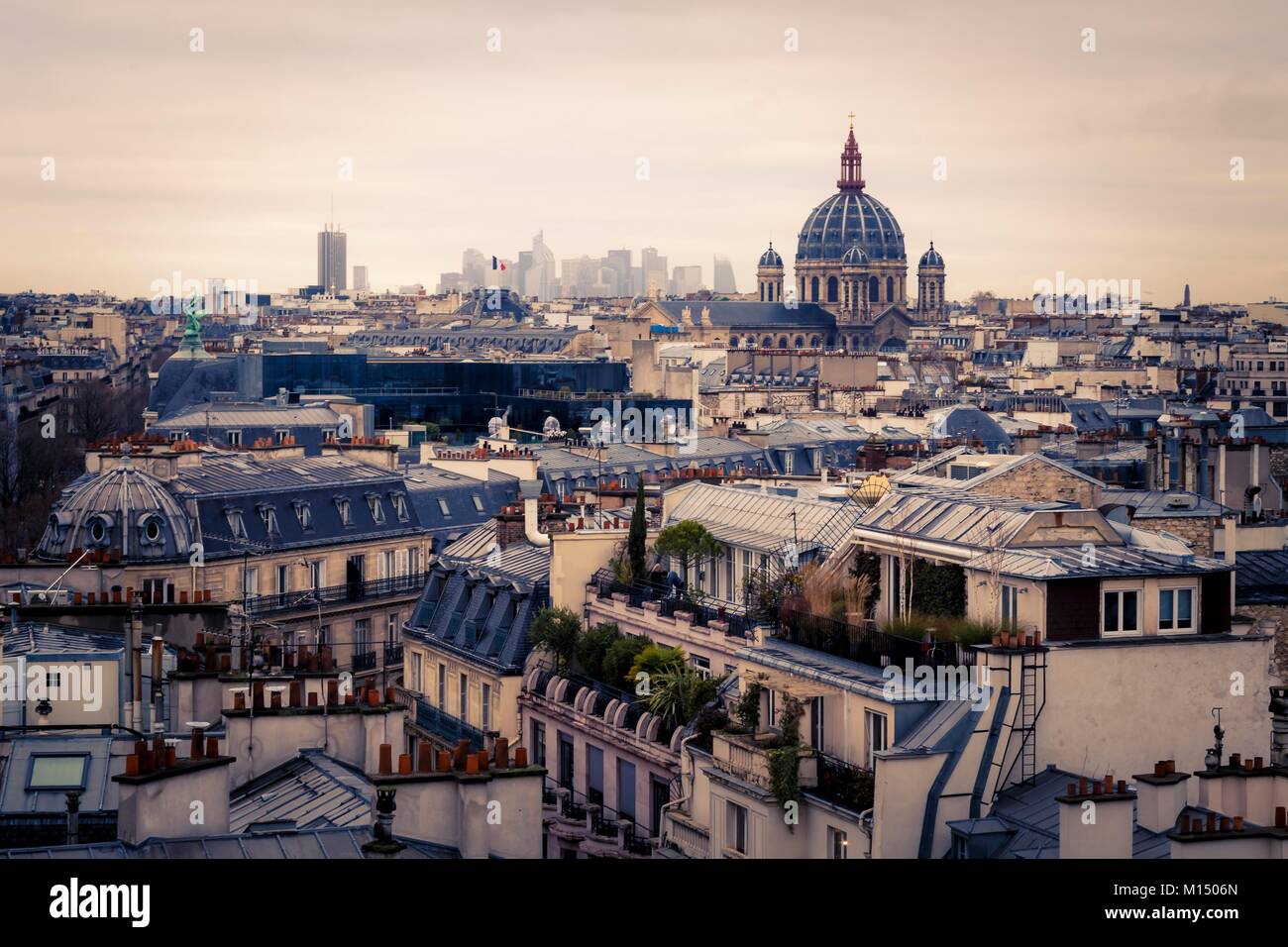 Vista sui tetti di Parigi, Francia attraverso i sobborghi guardando verso un lontano CBD e il quartiere finanziario all'orizzonte in un tonico immagine con vignette Foto Stock