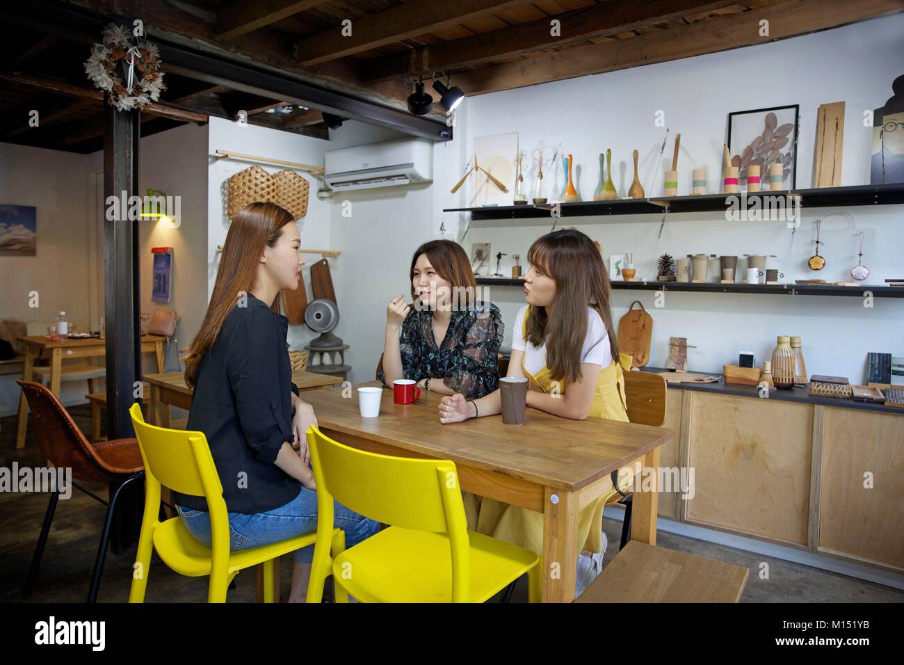Corea del Sud di Seul Gyedong, tre giovani donne seduti in un caffè pasticceria decorate con oggetti in legno Foto Stock