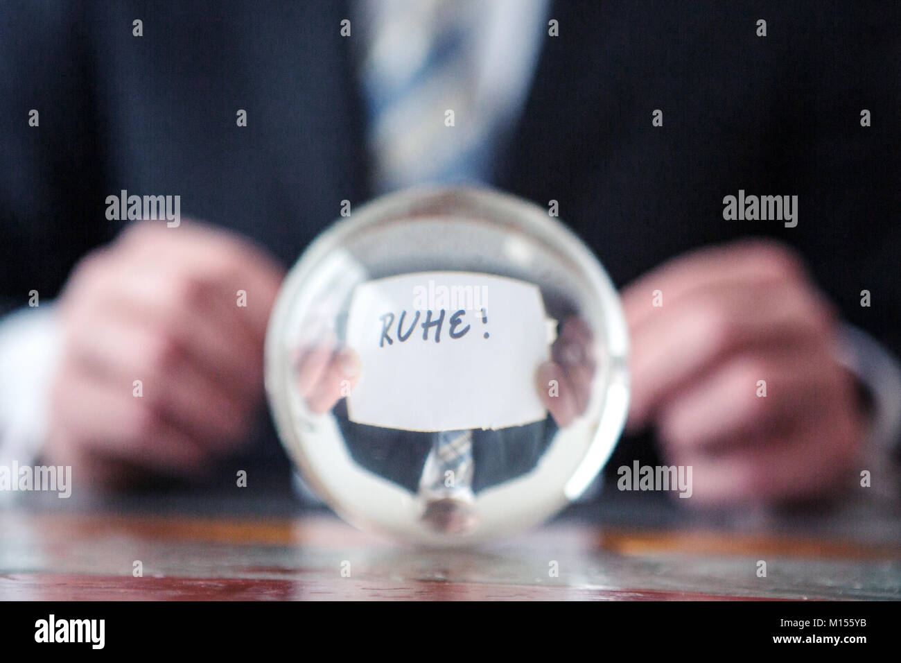 Primo piano di uomo con la carta con la parola tedesca per una tranquilla di fronte a sfera di vetro Foto Stock