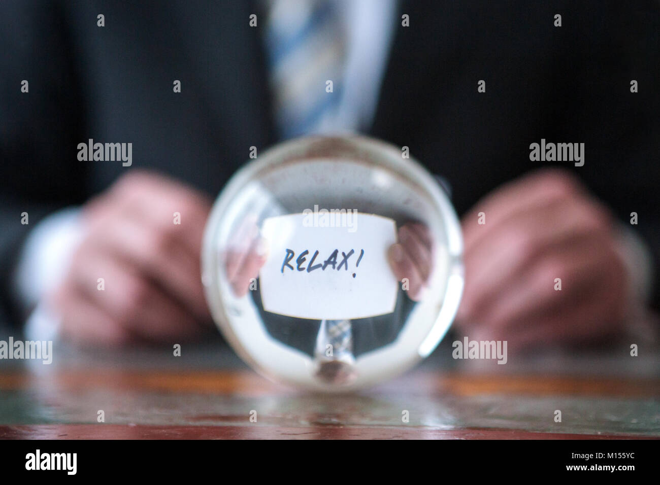 Primo piano di uomo con la carta con la parola rilassarsi di fronte a sfera di vetro Foto Stock