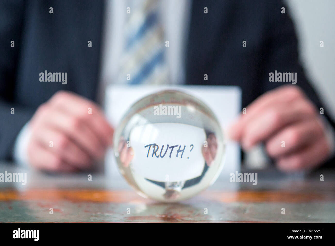 Primo piano di uomo con la carta con la parola di verità di fronte a sfera di vetro Foto Stock