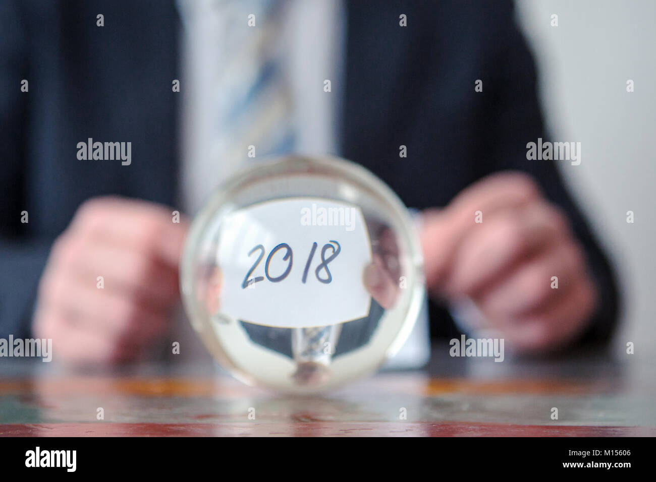 Primo piano dell'uomo tenendo la carta con i numeri 2018 davanti a sfera di vetro Foto Stock