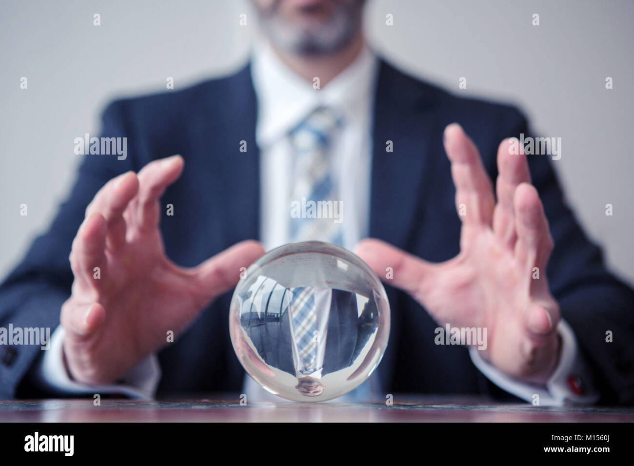Primo piano di imprenditore guardando a sfera di vetro sul tavolo Foto Stock