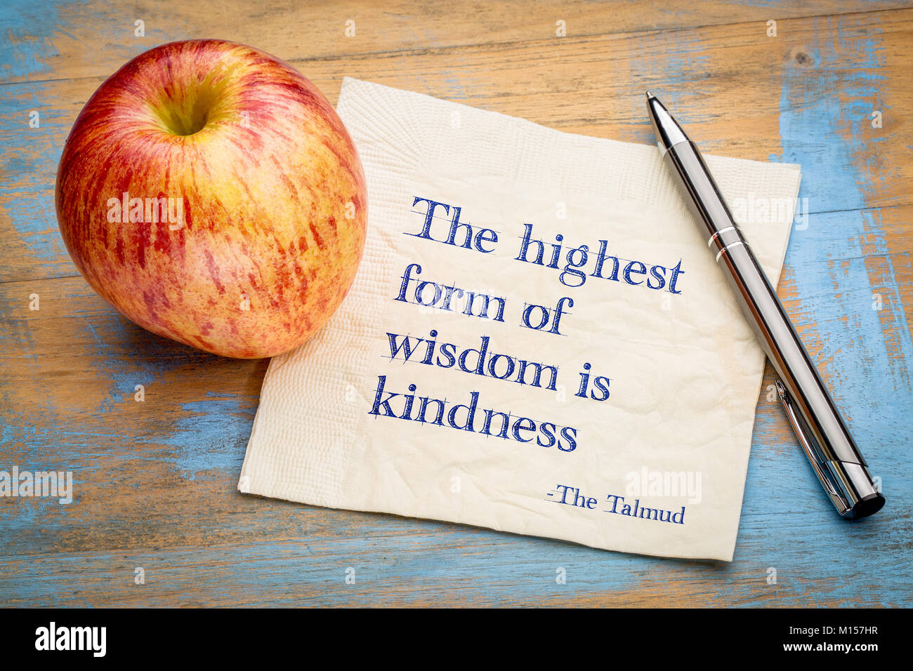 La più alta forma di saggezza è la gentilezza - scrittura su un tovagliolo con un fresco apple Foto Stock