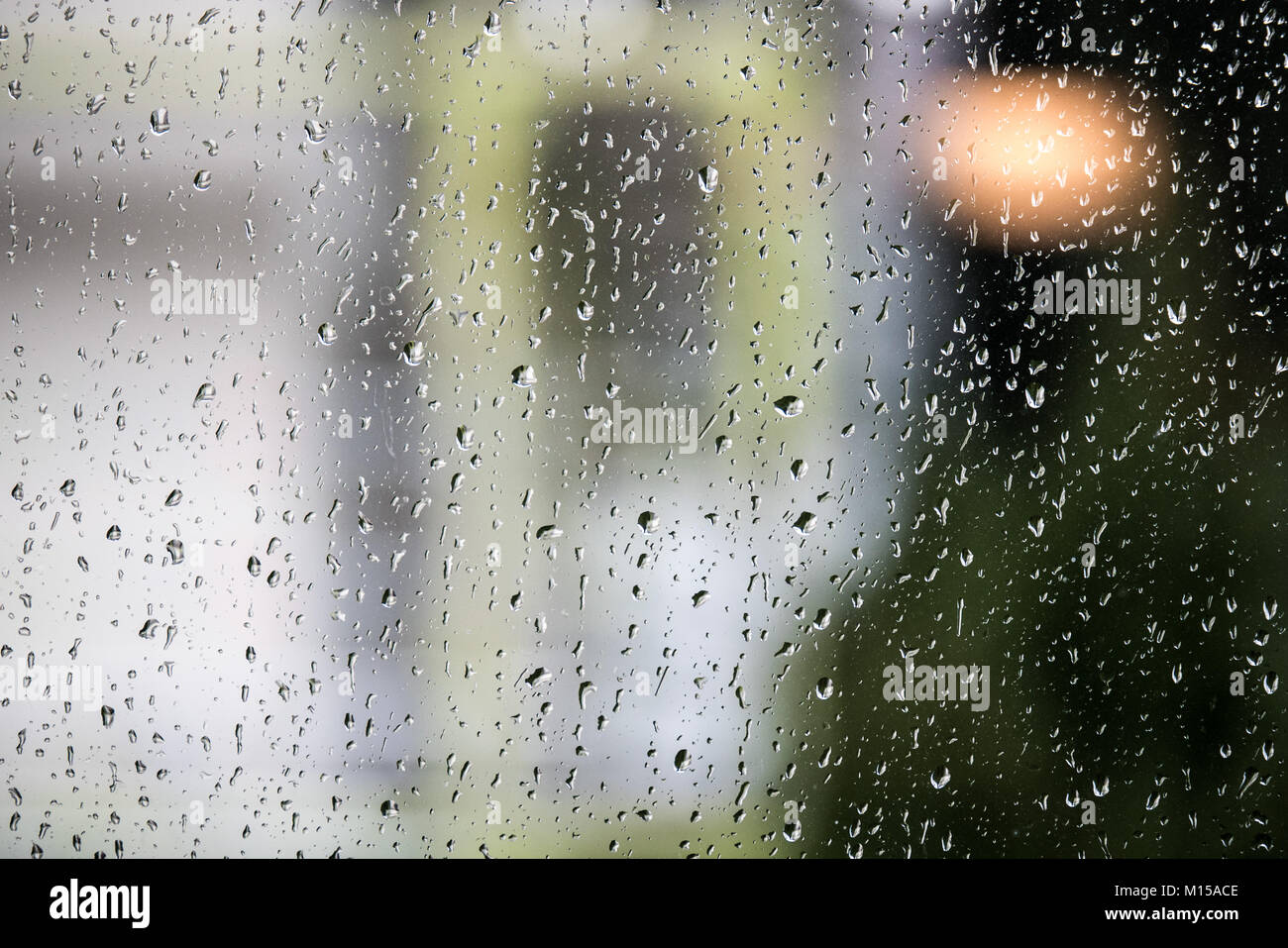 Gocce di pioggia su un vetro di finestra con un background di messa a fuoco Foto Stock