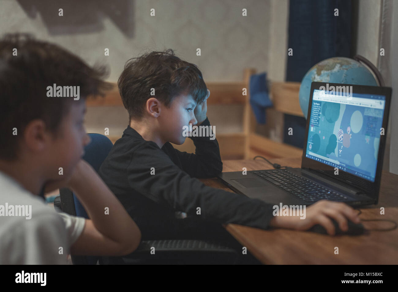 Ragazzi piccoli giocando multiplayer video gioco sul portatile a casa Foto Stock