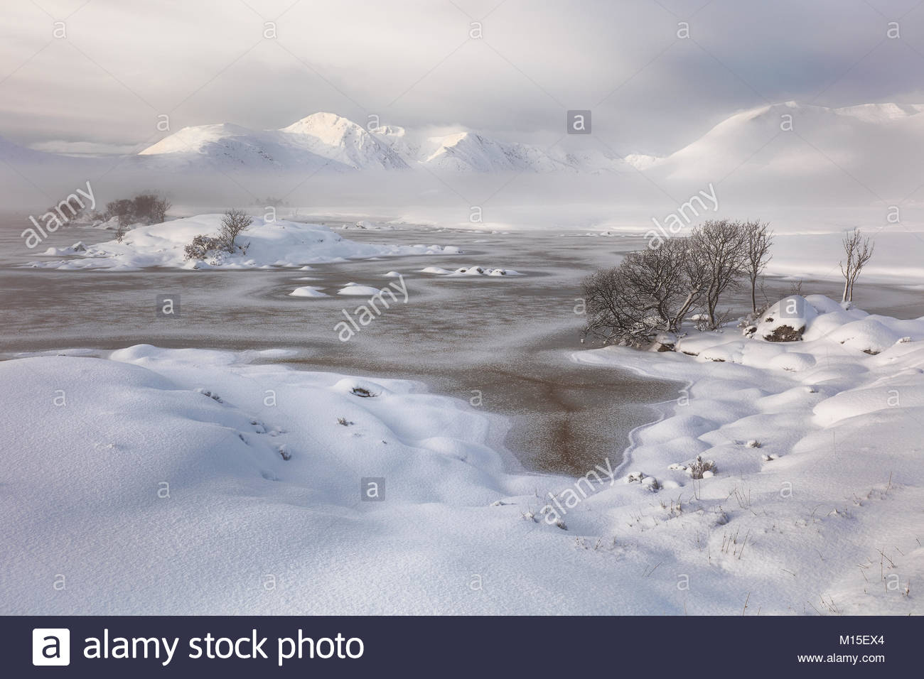 Una coperta di neve Rannoch Moor guardando sopra un congelati Lochan na h-achlaise al Misty Blackmount mountain range. Glencoe, Scozia Foto Stock