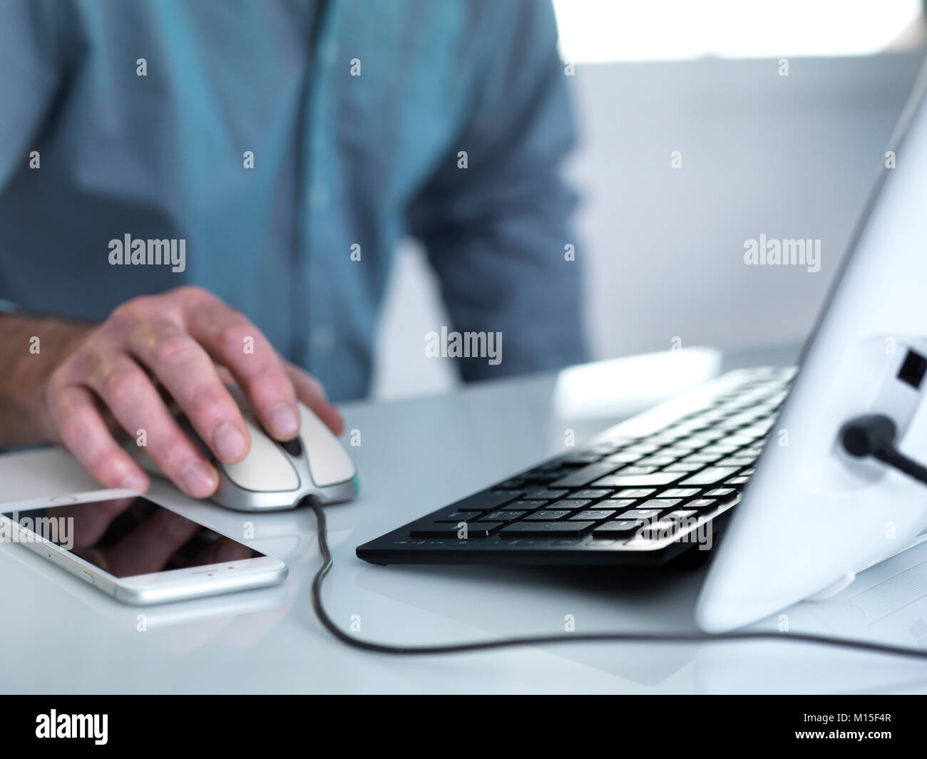 Modello rilasciato. L uso del computer. Uomo che lavora al PC con un telefono cellulare sulla scrivania. Foto Stock