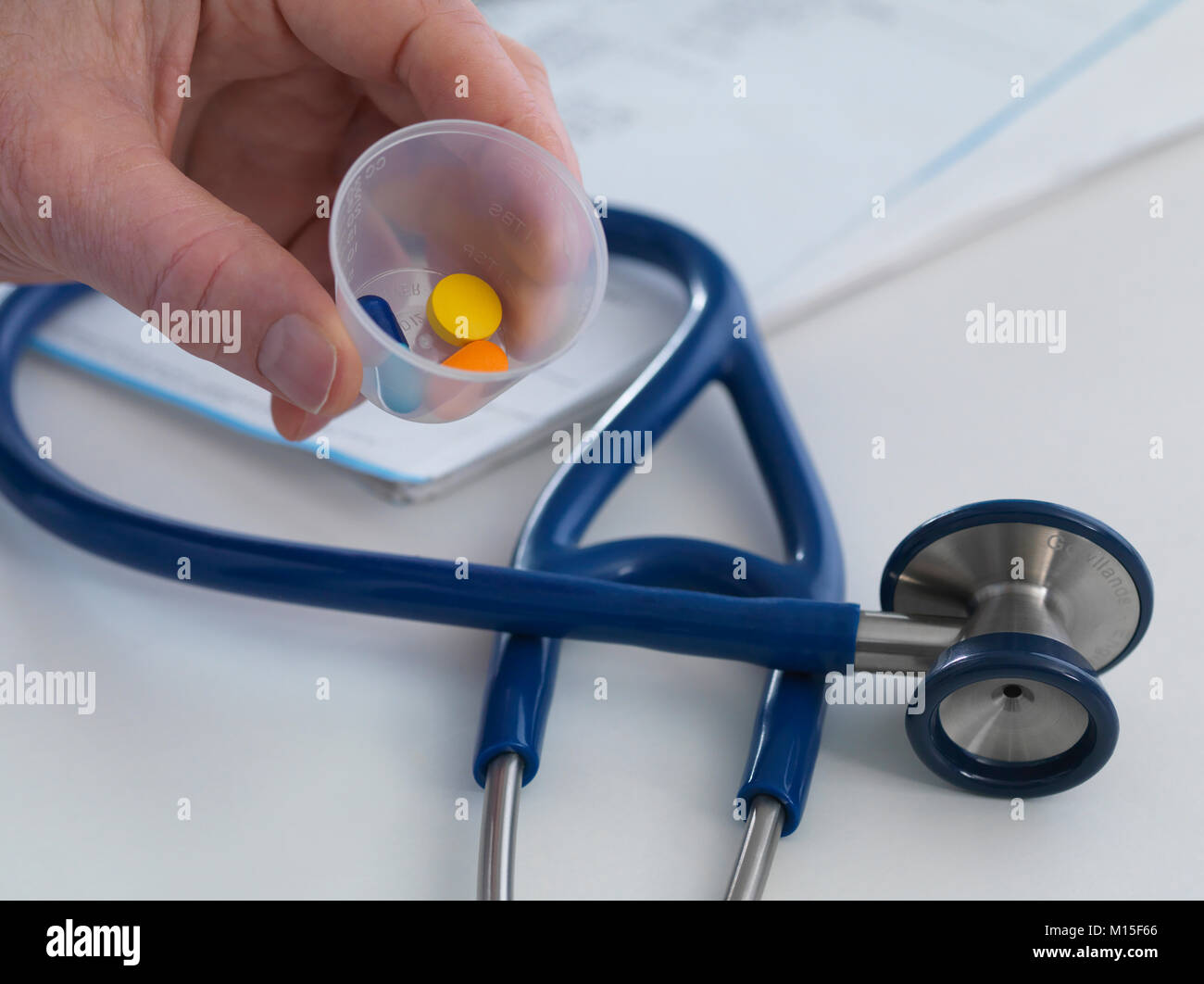 Modello rilasciato. Medico tenendo un bicchiere contenente la prescrizione di farmaci a portata di mano per il suo paziente. Foto Stock