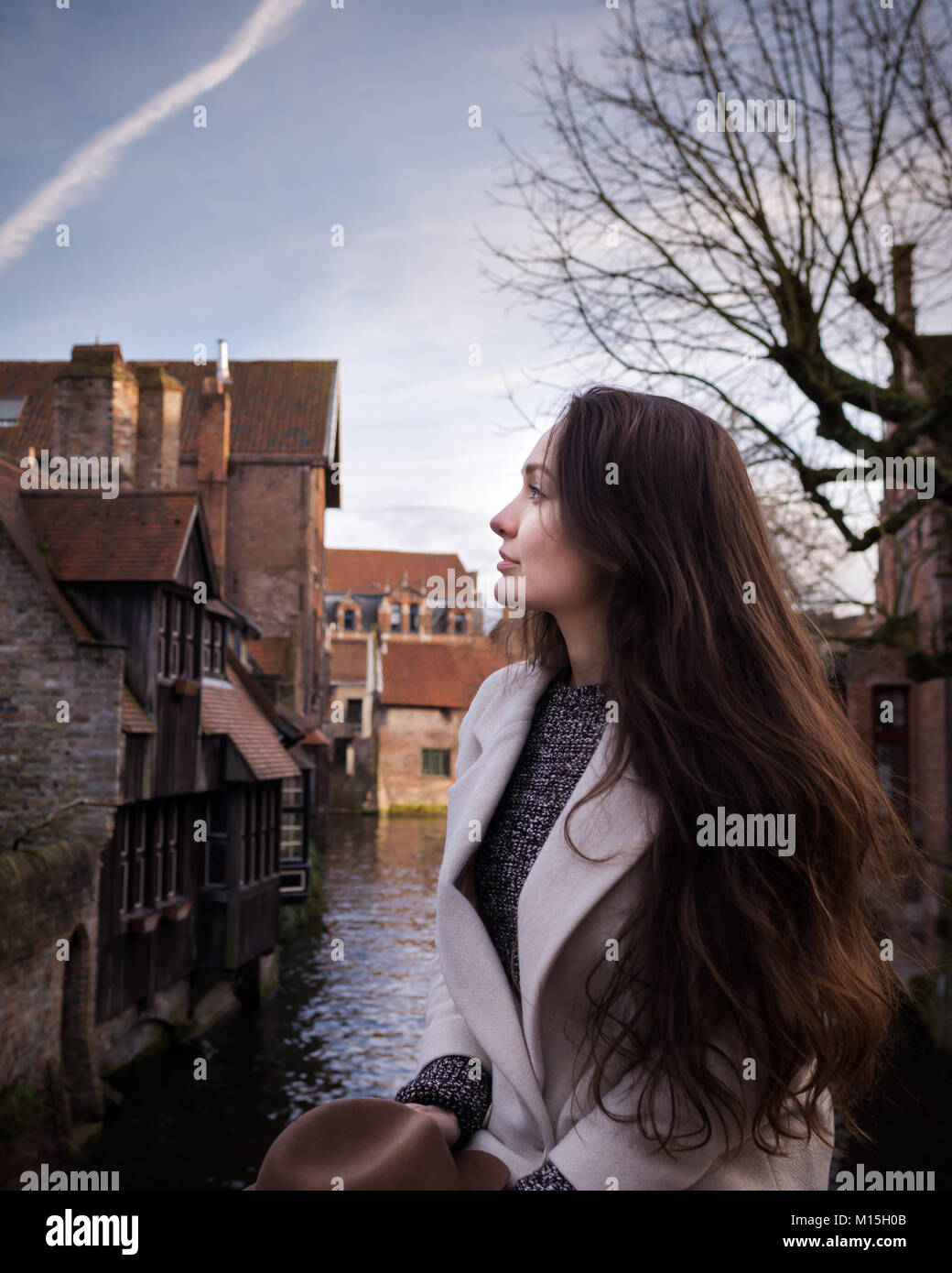 Turista femminile è ispirata da atmosfera del centro storico di Brugge, in Belgio. Giovane donna di stare in un posto romantico con edifici d'epoca Foto Stock