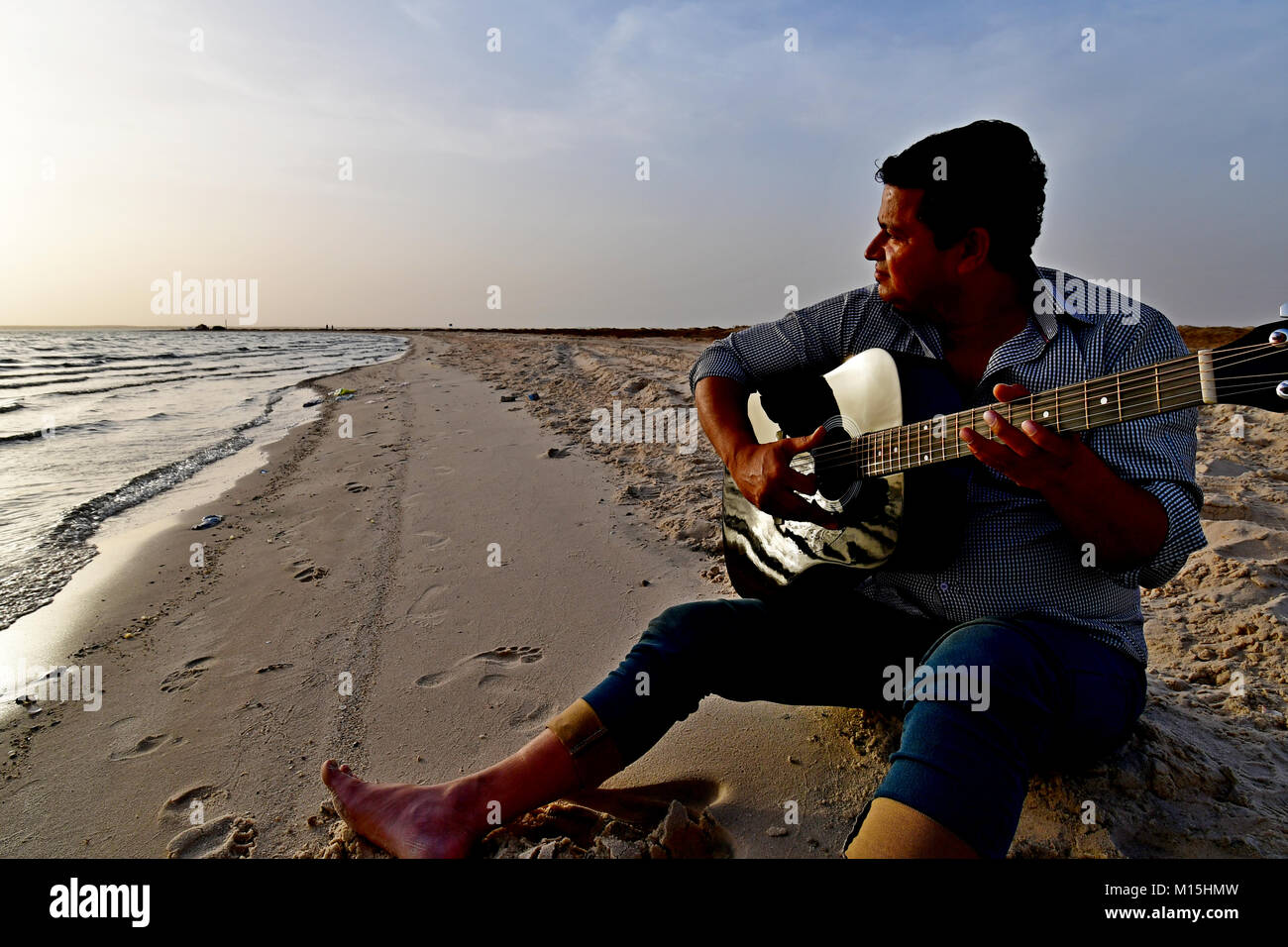 Amici in spiaggia al tramonto la riproduzione di musica per chitarra e camminare sulla spiaggia e dispone di un momento di relax. Foto Stock