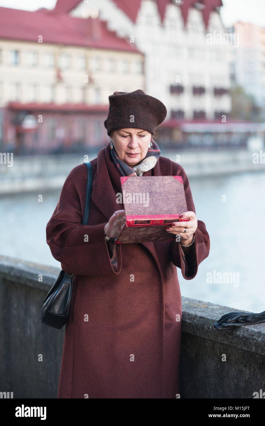 Una donna anziana in un cappotto utilizza una tavoletta digitale Foto Stock