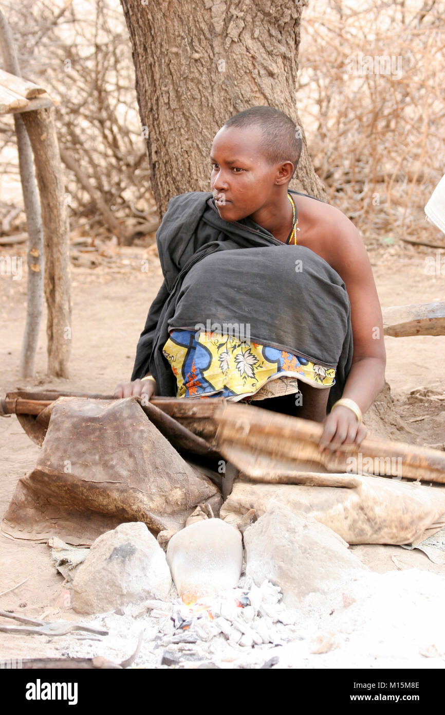 Uomo Datoga prepara e illumina il falò utilizzando una pelle di capra a soffietto. Fotografato in Africa, Tanzania, Lago Eyasi Foto Stock
