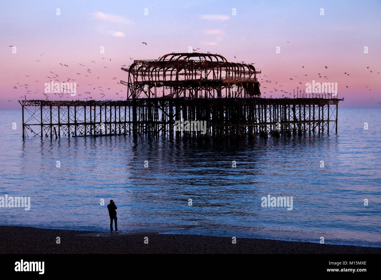 Brighton, Regno Unito, abbandonata molo Ovest, il telaio metallico di lavoro dei derelitti Molo Ovest al tramonto, il mare è blu riflettente e rosa e il cielo Foto Stock