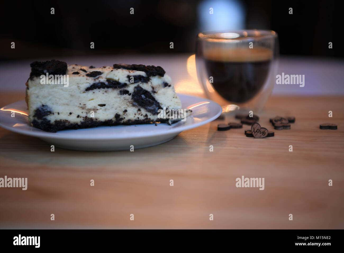Cibi fatti in casa di biscotti al cioccolato cheesecake con amore in legno cuore decorazioni e illuminazione con una bevanda calda del caffè espresso in background Foto Stock