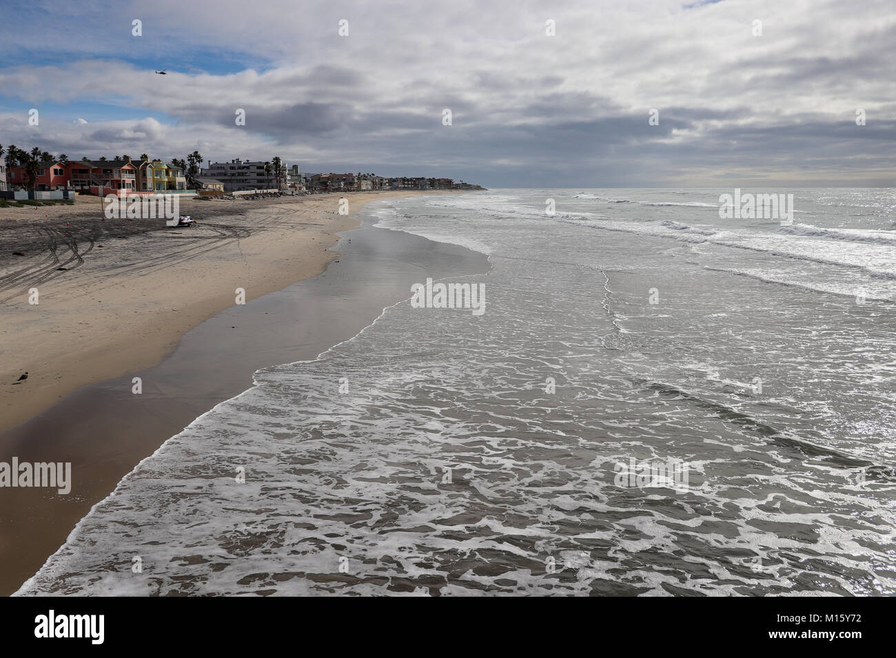 Vista la bellissima e ampia spiaggia sabbiosa dal molo Imperial Beach in California con la bassa marea,quando la sabbia è bagnato,schiumosa e riflessiva, cielo tempestoso Foto Stock