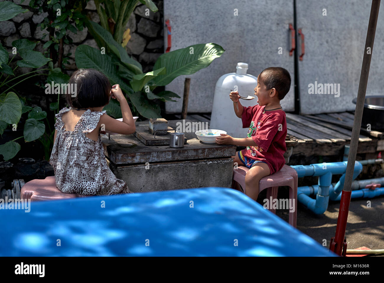 I bambini a mangiare fuori in Thailandia backstreet. Sud-est asiatico scena di strada. Foto Stock