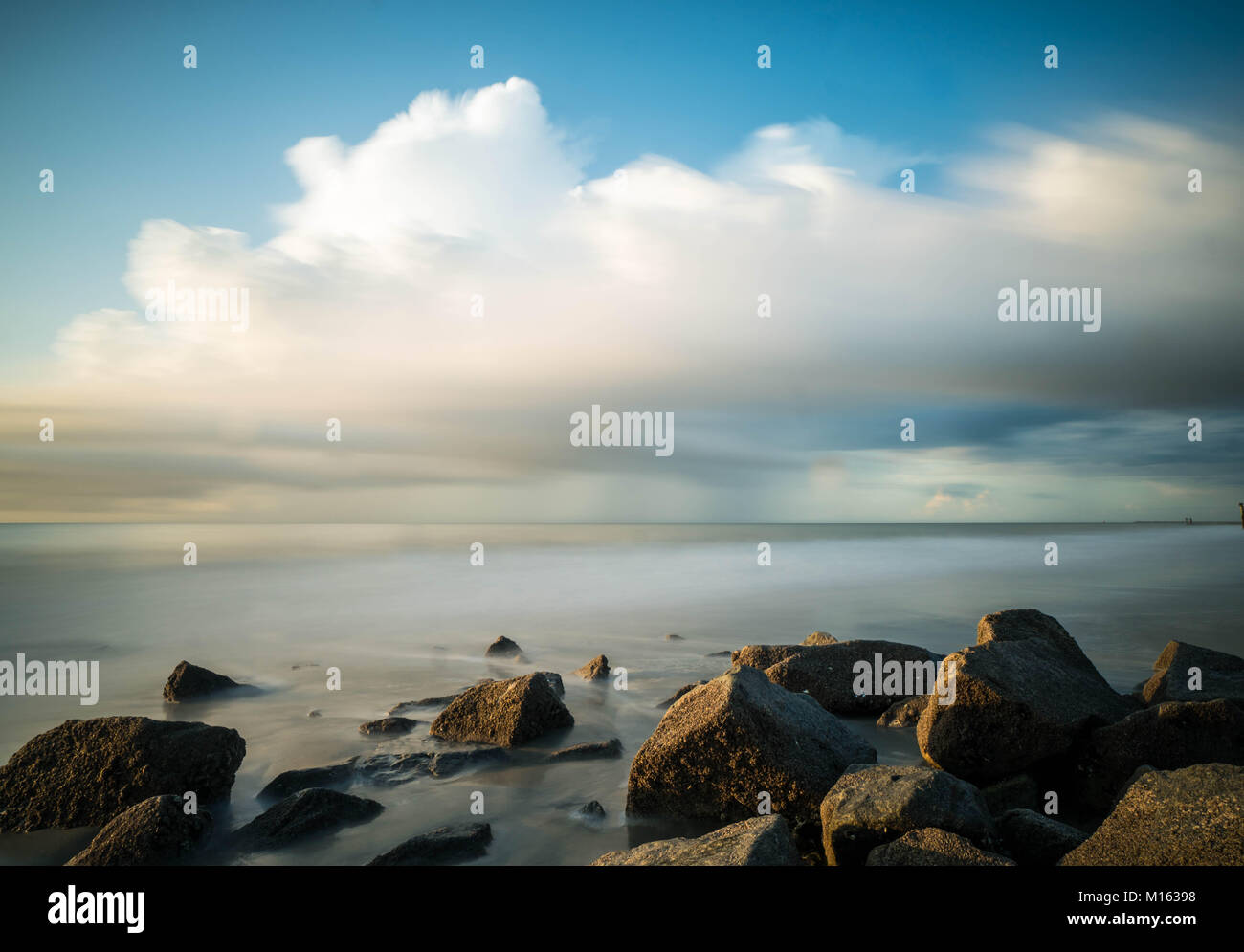 Tranquilla marina costiera all'alba con un espressivo del cielo e le rocce in primo piano Foto Stock